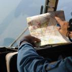 Un miembro de las Fuerzas Aéreas vietnamitas revisando un mapa a bordo de un helicóptero que vuela sobre la zona sur de las aguas de Vietnam.