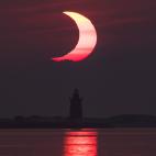 LEWES, DELAWARE - JUNE 10: In this handout image provided by NASA, a partial solar eclipse is seen as the sun rises behind the Delaware Breakwater Lighthouse on June 10, 2021 in Lewes, Delaware. Northeast states in the U.S. will see a rare eclip...