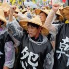 Tres manifestantes llevan chalecos con lemas en Taipei.