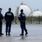 Policemen stand outside the TotalEnergies fuel depot of Mardyck, near Dunkirk, northern France, on October 13, 2022, where essential striking workers were ordered by the French government to return to work. - Unions are seeking pay hikes in resp...
