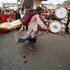 Un devoto gira mientras toca el tambor para equilibrar su peso mientras otro cuelga de su espalda, en Lahore, Pakistán.