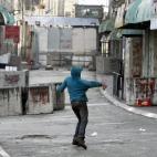 Un adolescente palestino tira piedras frente al puesto de control fronterizo de la ciudad cisjordana de Hebrón. Al poco de hacerse esta foto, apareció un soldado israelí y lanzó gases lacrimógenos.