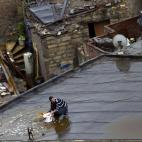 Un joven retira el agua del tejado tras las fuertes lluvias en El Cairo. Los medios locales han informado de que el frío ha llegado a Egipto.