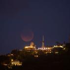 Vista del eclipse total de Luna tras el parque de atracciones del Tibidabo