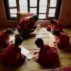 Tandi Dorji se sienta en un grupo con otros jóvenes monjes repitiendo sagradas escrituras en un monasterio de Thimphu en junio de 2013.