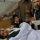 Un hombre consuela a los compañeros del niño herido que permanece en la cama de un hospital local. (AP Photo/Mohammad Sajjad)