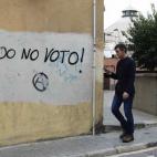Un joven camina junto a un graffiti en el que puede leerse "Yo no voto" pintado cerca de un colegio electoral en Mataró (Barcelona).