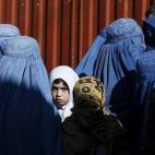Una niña observa entre mujeres afganas que esperan ayuda para el invierno del Alto Comisionado de las Naciones Unidas para Refugiados en Kabul, Afganistán.