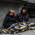 Dos sirios, sentados en la acera mientras cae la nieve en Estambul, Turquía.