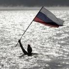 Un hombre ondea una bandera nacional rusa mientras nada en el Mar Negro, en una playa del puerto de Crimea Yevpatoriya.