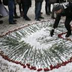 Un hombre coloca flores para formar un corazón como homenaje a las víctimas del atentado contra el semanario satírico Charlie Hebdo, en Moscú (Rusia). Tres hombres encapuchados y armados con fusiles kalashnikov mataron el pasado 7 de enero a...