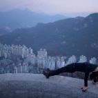 Una deportista hace estiramientos al amanecer, con una vista panorámica de la ciudad de Seúl de fondo.