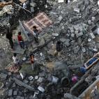 Ni&ntilde;os de Gaza buscan entre los restos de su casa algunas pertenencias.