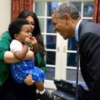 President Barack Obama greets a little boy held by Ferial Govashiri, Personal Aide to the President, in the Outer Oval Office, Oct. 24, 2014. (Official White House Photo by Pete Souza)