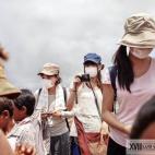 Una turista japonesa tapada con una mascarilla hace fotos a los niños que trabajan en el basurero.