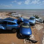 Una pila de coches, destrozados en la orilla por los efectos de la riada