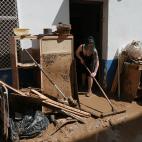 Una mujer trata de eliminar el barro de su casa, entre muebles destrozados, tras la inundaci&oacute;n en Alcanar