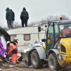Agents and bulldozers dismantle shacks as people stand on a caravan's roof on March 1, 2016 in the 'Jungle' migrant and refugees camp in the French northern port city of Calais. Workers were due to start a second day of destruction in the southe...