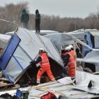 Agents dismantle shacks as two people stand on a shelter's roof on March 1, 2016 in the 'Jungle' migrant camp in the French northern port city of Calais. Workers were due to start a second day of destruction in the southern half of the camp, whe...