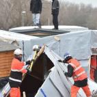 Agents dismantle shacks as two migrants stand on a shelter's roof on March 1, 2016 in the 'Jungle' migrant camp in the French northern port city of Calais. Workers were due to start a second day of destruction in the southern half of the camp, w...