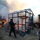 CALAIS, FRANCE - FEBRUARY 29: A migrant attempts to extinguish a fire as a hut burns as police officers clear part of the 'jungle' migrant camp on February 29, 2016 in Calais, France The French authorities have begun dismantling part of the mi...