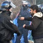 A migrant speaks with an anti-riot policeman on February 29, 2016, during the dismantling of half of the 'Jungle' migrant camp in the French northern port city of Calais. Two bulldozers and around 20 workers began destroying makeshift shacks, wi...