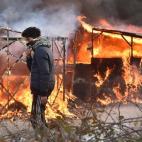 A migrant walks past shacks burning during the dismantling of half of the 'Jungle' migrant camp in the French northern port city of Calais, on February 29, 2016. Clashes broke out between French riot police and migrants on February 29 as bulldoz...