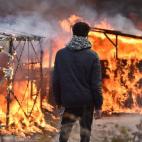 A migrant looks at shacks burning during the dismantling of half of the 'Jungle' migrant camp in the French northern port city of Calais, on February 29, 2016. Clashes broke out between French riot police and migrants on February 29 as bulldozer...