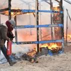A migrant tries to extinguish a fire during the dismantling of half of the 'Jungle' migrant camp in the French northern port city of Calais, on February 29, 2016. Clashes broke out between French riot police and migrants on February 29 as bulldo...