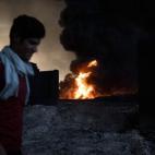 Un hombre pasea junto a una de las zonas que arden tras la ofensiva contra el Estado Islámico en Mosul
