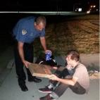 Agente de policía le ofrece pizza y refresco a un hombre sin hogar que había estado durmiendo al lado del camino.