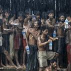 Inmigrantes que fueron encontrados en un barco en el mar, intentan conseguir agua durante una tormenta en el campo de refugiados cerca de Kanyin Chaung, en Myanmar.