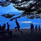 Un chico se balancea de una rama de un árbol en una playa de Bujumbura.