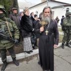 Un sacerdote ortodoxo contrasta con el militar armado.