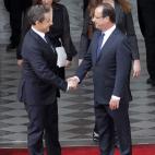 France's outgoing president Nicolas Sarkozy (L) shakes hands with France's president-elect Francois Hollande (R), next to Carla Bruni-Sarkozy (2nd row R) and Hollande's companion Valerie Trierweiler, as they are about to leave the Elysee preside...