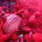 Varias personas cubiertas de polvo de color rojo participan en la celebración del festival hindú de Holi en el templo de Radha Rani, en Mathura, en la India.