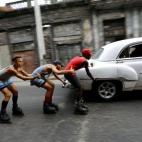 Un grupo de adolescentes en patines se agarran entre ellos mientras los lleva un coche de la vendimia a lo largo de las calles de La Habana.