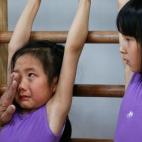 El entrenador de esta niña le limpia las lágrimas y le consuela cuando se sentía cansada a mitad de las clases de gimnasia en la Escuela de Atletismo Yangpu en Shanghai, China.