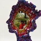Un pensionista de Chelsea posa a través de un diseño floral de la Reina Isabel para El Chelsea Flower Show de Londres, la feria de jardinería más importante del mundo.