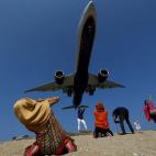 Un grupo de turistas posan para tomarse fotos mientras pasa un avión en Tailandia.