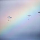 Un grupo de paracaidistas rusos saltan de un avión durante un entrenamiento militar. El momento coincide mientras sale el arcoíris.