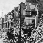Muchachos se cuelgan de un poste de luz en medio de escombros producidos por un bombardeo en Londres en 1940.