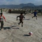 Niños afganos juegan al fútbol cerca de un cementerio en una colina en Kabul el 12 de abril de 2014.