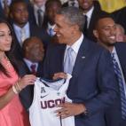 El presidente estadounidense Barack Obama sonríe después de recibir una camiseta de Bria Hartley (a la izquierda) durante un evento en honor de los NCAA 2014.