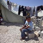 Personas y niños permanecen fuera de sus tiendas de campaña en un campo temporal para refugiados sirios en la ciudad de Marj, en el este de Líbano, cerca de la frontera con Siria, el lunes 20 de mayo de 2013. (AP Foto/Hussein Malla)