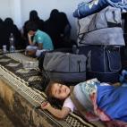 Una niña de una familia siria que huyó de su casa debido a los combates entre el ejército y los rebeldes duerme junto a las pertenencias de su familia, en el cruce fronterizo de Bab Al-Salameh, con la esperanza de entrar en uno de los campame...