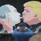 Un viandante fotografía un mural que muestra al presidente electo de Estados Unidos, Donald Trump, echando el humo de un porro en la boca del presidente ruso, Vladimir Putin. El grafiti se encuentra en un restaurante de Vilnius (Lituania).