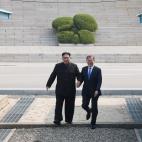 Kim y Moon sonr&iacute;en mientras cruzan la frontera militarizada juntos.