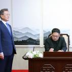 Kim firma el libro de visitas de la Peace House antes de la primera reuni&oacute;n de la cumbre bajo la mirada de Moon.