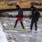 Dos jóvenes cruzan un lago congelado en un parque de Skopje, Macedonia.